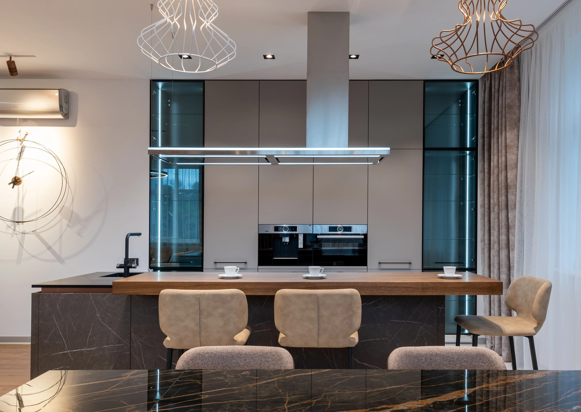 Illustrative apartment kitchen with an island, bar stools and built-in ovens